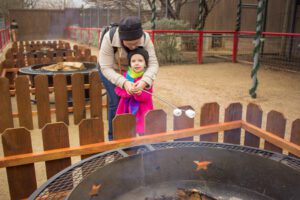 Two Zoo guests roasting marshmallows over a fire pit 