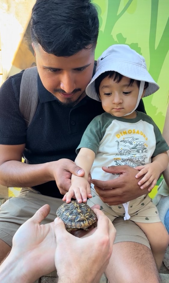 Two zoo guests having a private encounter with Waffles the pancake tortoise.